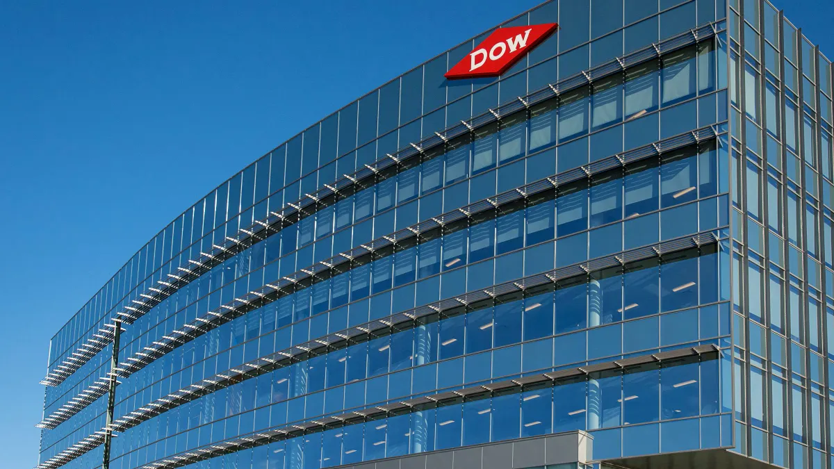 A corporate building with glass windows and a red and white Dow logo sign on top right corner.