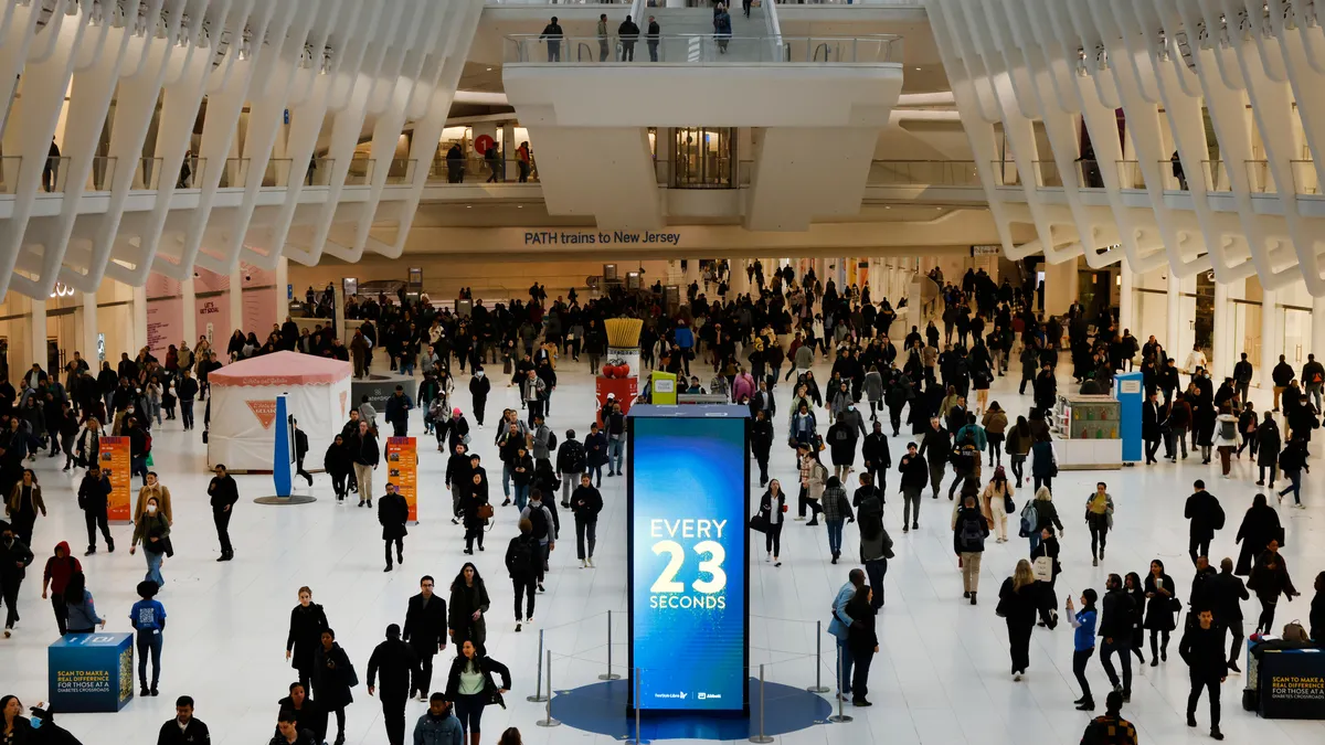 People walk around a vertical screen that reads "Every 23 Seconds"