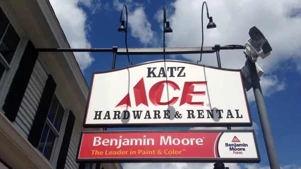 A store sign that says "Ace Hardware & Rental," against a bright blue sky with puffy white clouds.