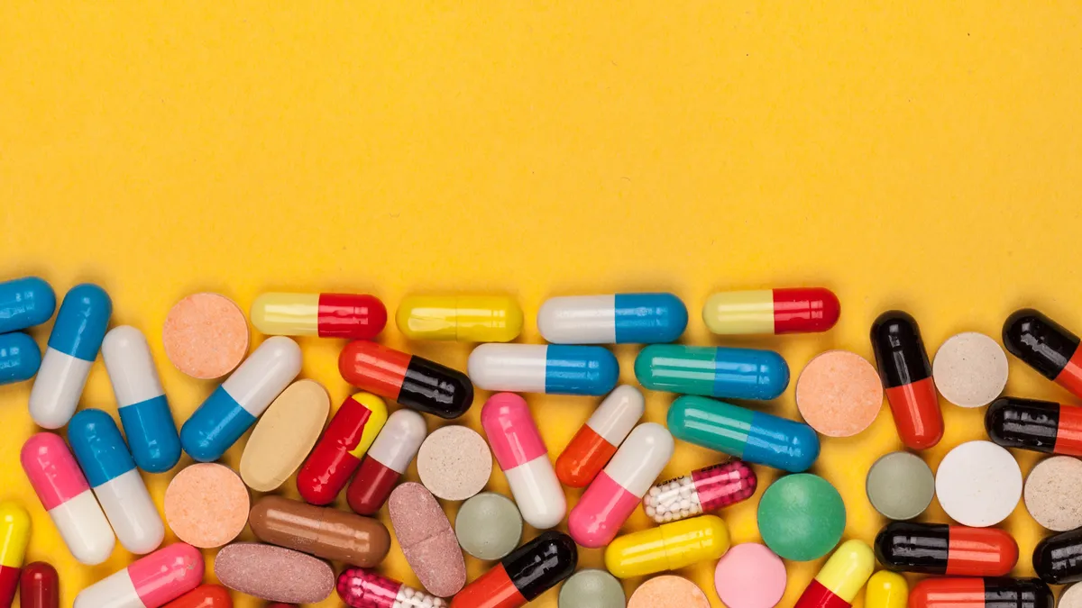 Colorful drug capsules against a yellow background