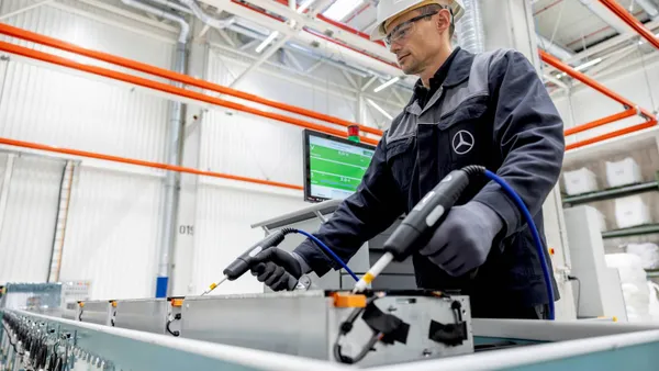 A worker at the new Mercedes-Benz battery facility in Germany prepares a battery module for recycling.