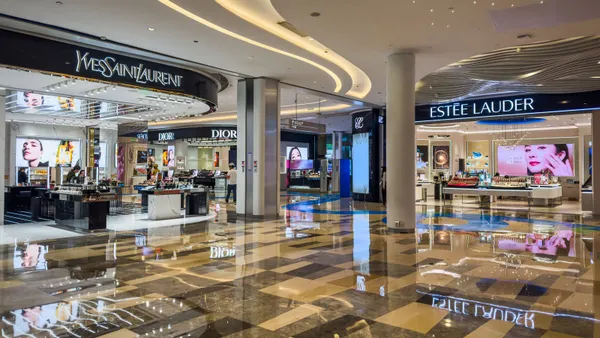 The interior of a well-lit mall shows beauty counters from YSL, Estee Lauder and Dior.