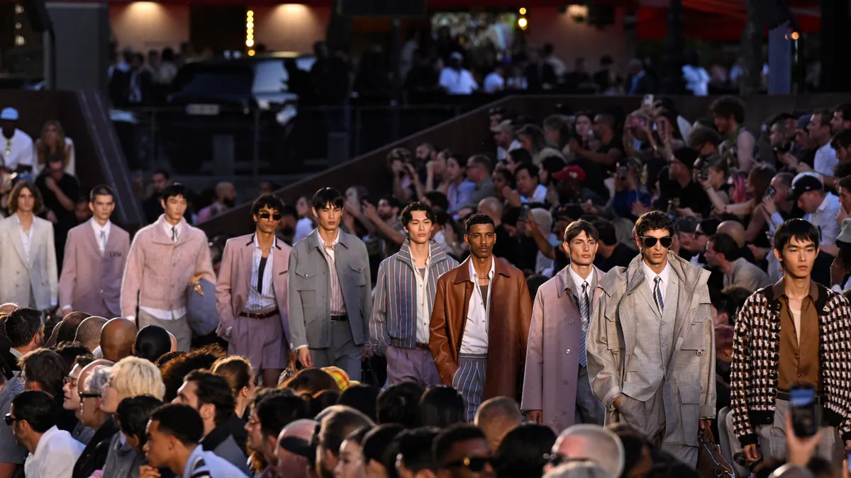 Male models walk down a fashion runway.