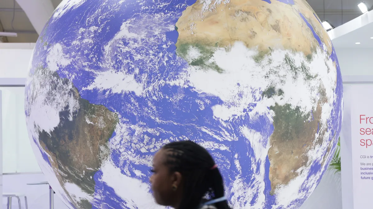 A conference participant walks past a spinning representation of Planet Earth during the UNFCCC COP27.