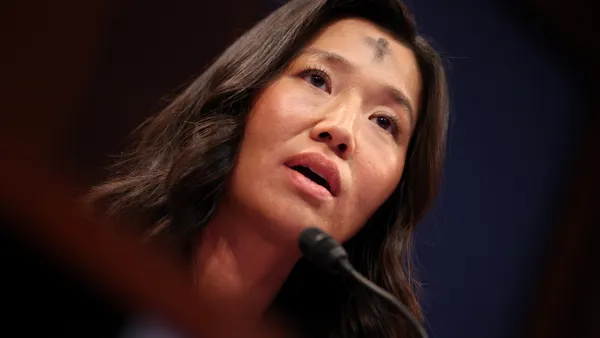 Woman with mark in shape of a cross on forehead speaks into microphone