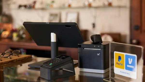 PayPal and Venmo logos on sign sitting on merchant's counter next to a clerk's digital display for payments.