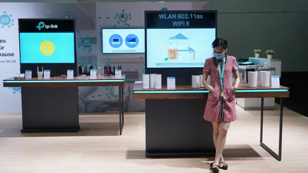 A woman wearing a surgical mask stands in front of a booth for the Chinese networking company TP-Link at a German consumer electronics trade show.