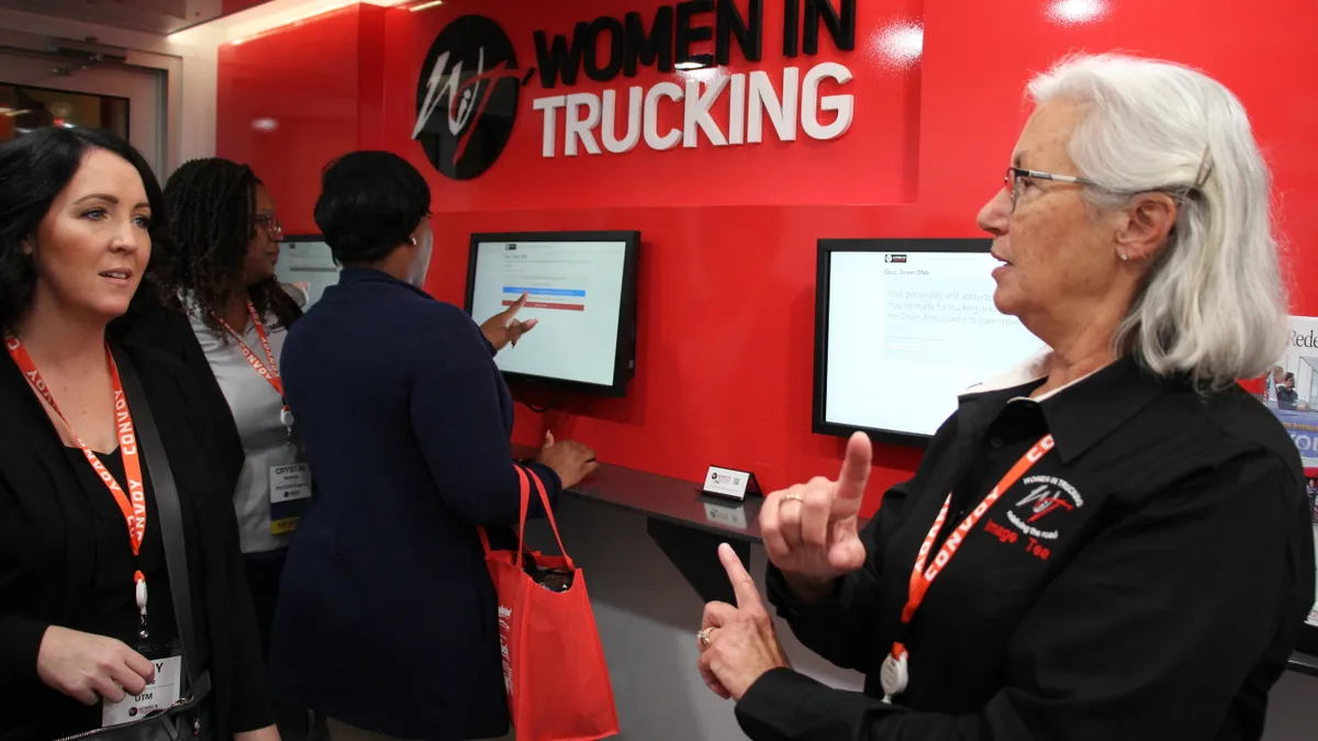 A Women In Trucking Association representative and conference attendee talk inside an educational trailer.