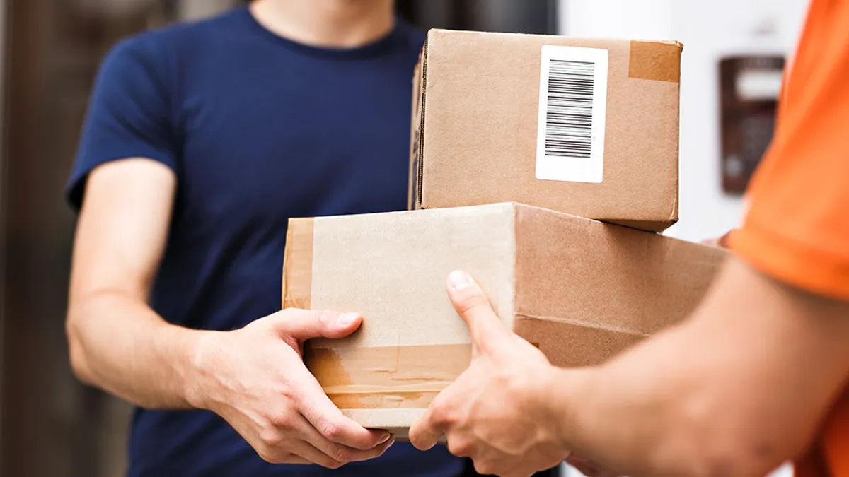 A person wearing an orange T-shirt and a name tag is delivering parcels to a client. Friendly worker, high quality delivery service.