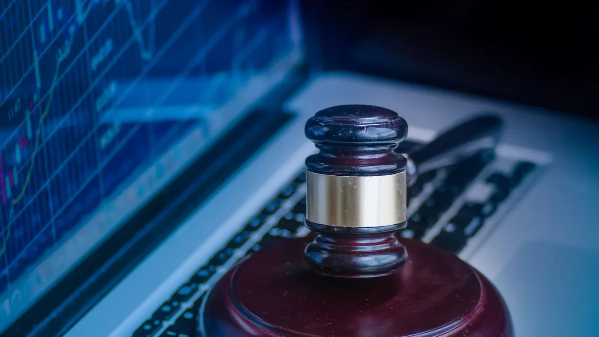 Judge's gavel on keyboard with glowing computer screen monitor background.