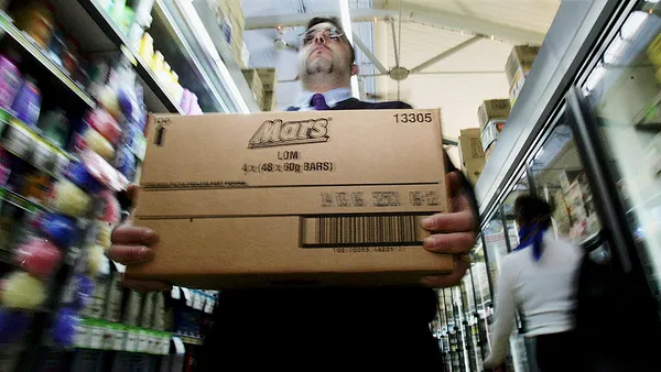 A man seen carrying a box of Mars Bars in a store.