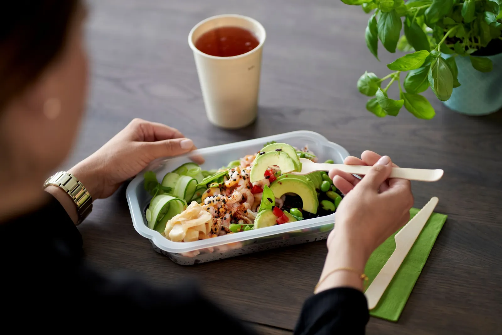 A person eats food out of a plastic container.
