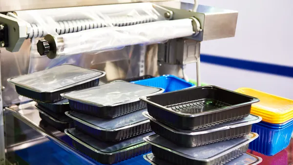 Stacks of black plastic food containers being packaged