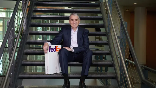 A person poses with a FedEx package while sitting on stairs.