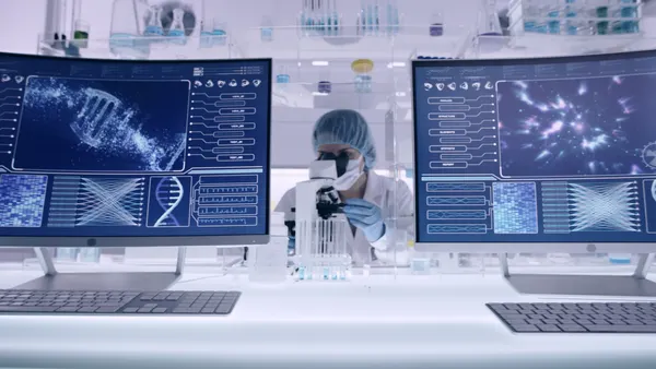 Researcher reviews DNA sequencing data on computer screens.