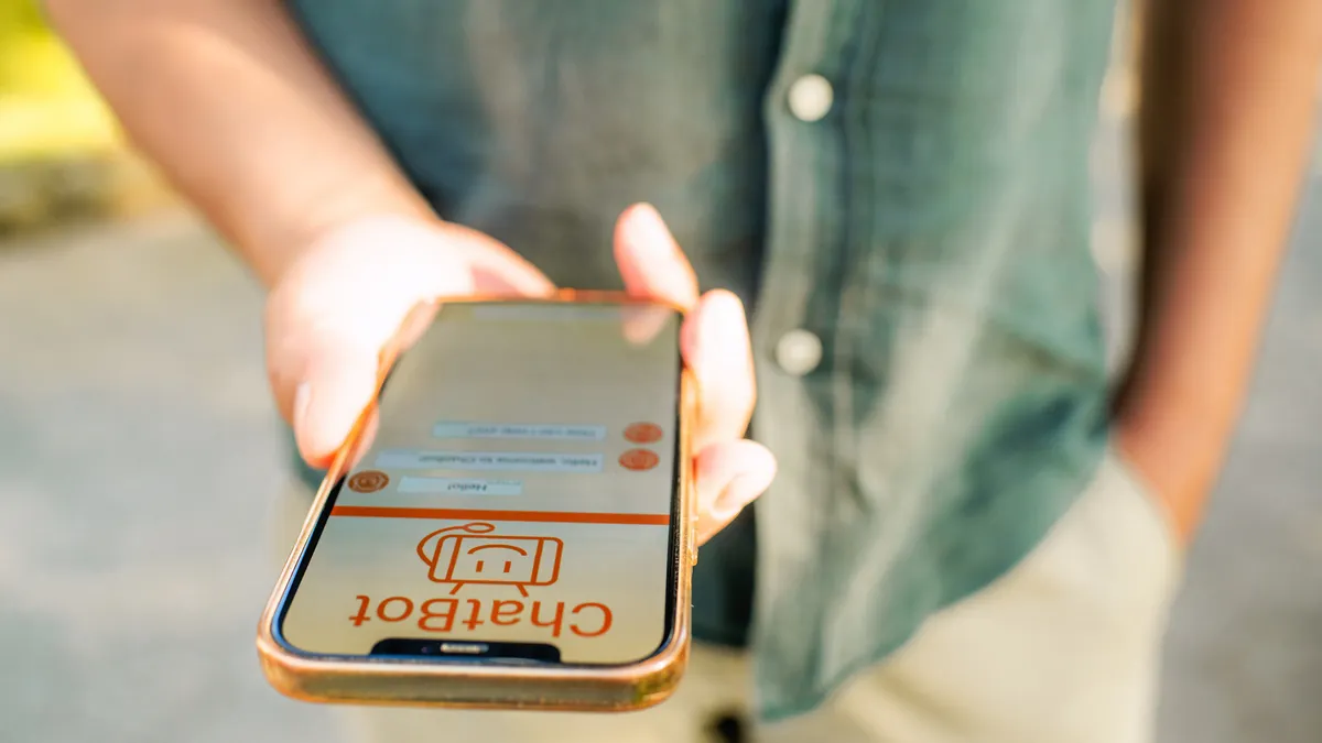 A close up of a man's hand holding a phone displaying a conversation with a chatbot.
