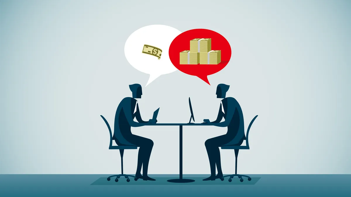 Two workers sit at a lunch table discussing pay.