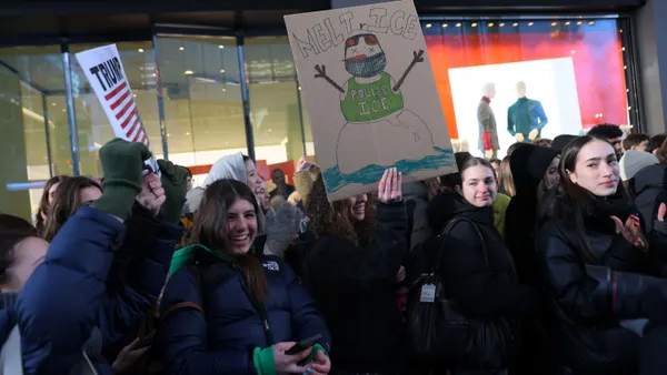 In a crowd of protesters, one person holds up a sign with a melting snowman that says "Melt ICE."