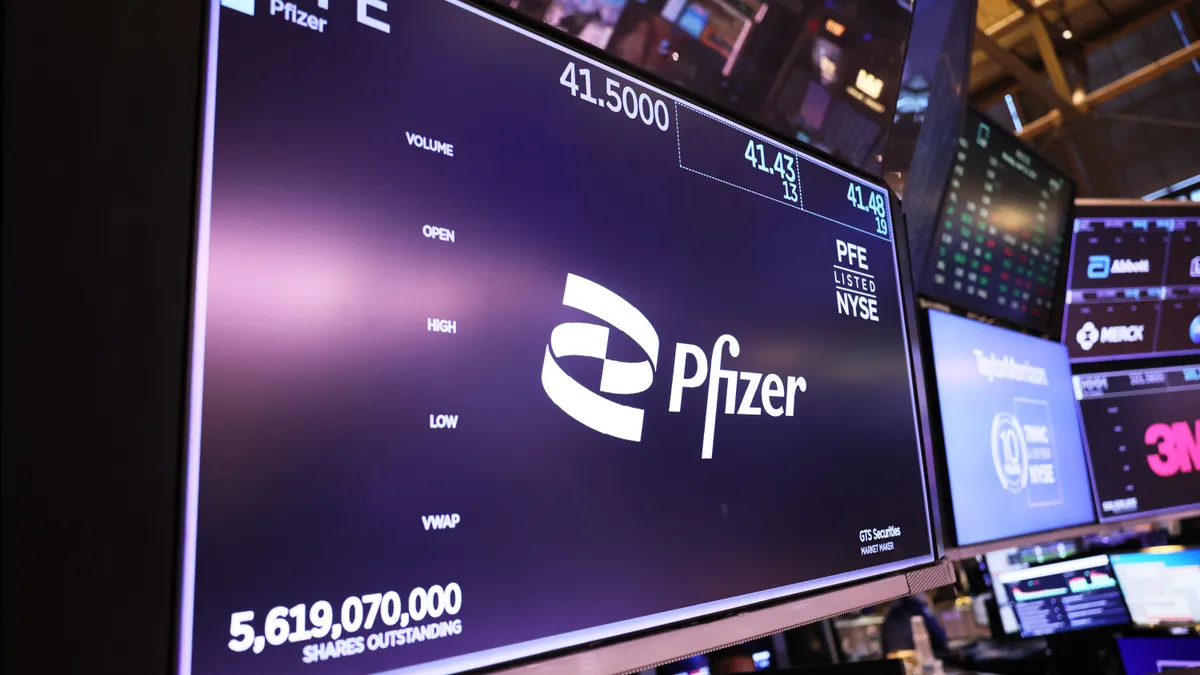 A computer screen shows the Pfizer logo and stock price at the New York Stock Exchange