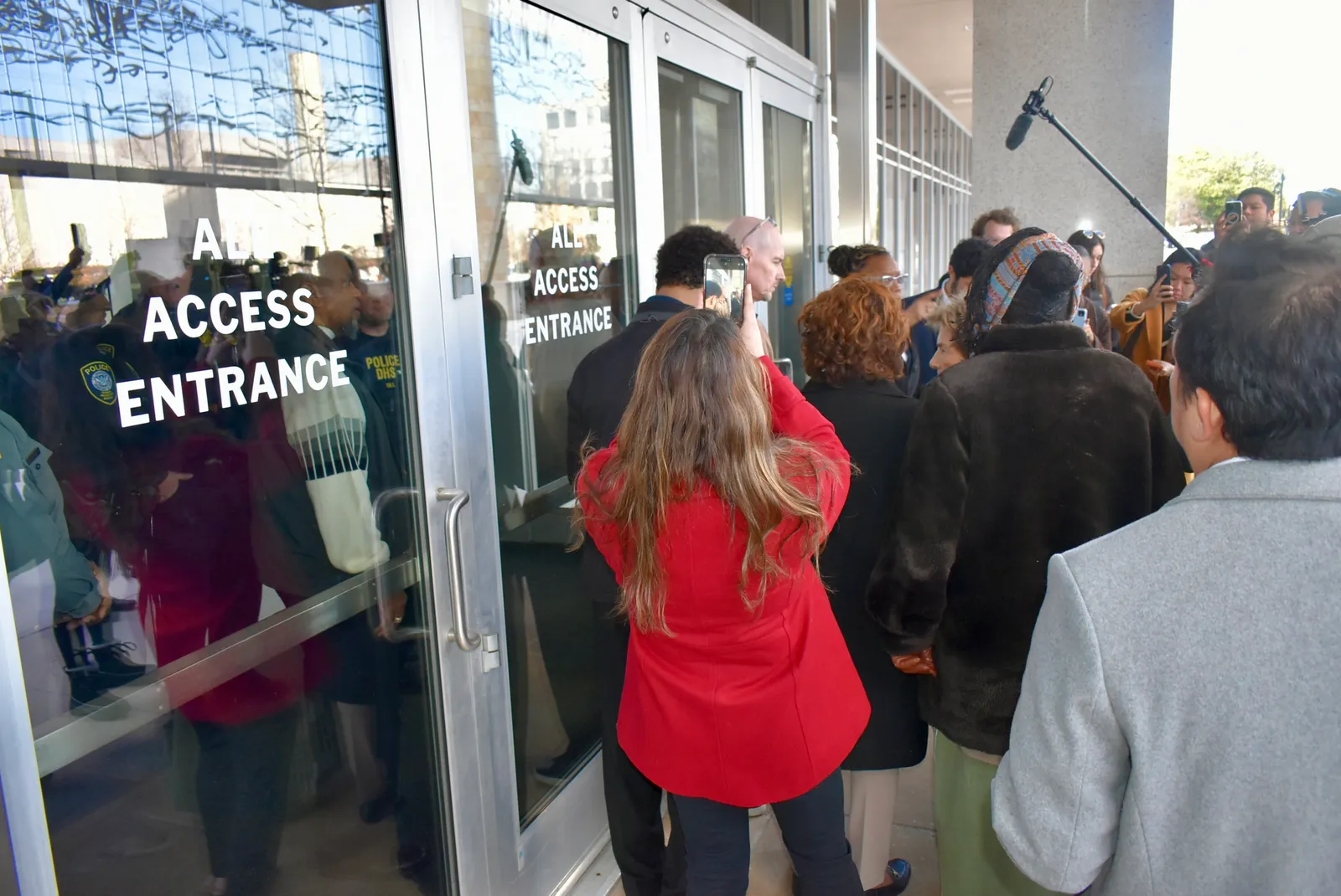 A group of people are standing in front of glass doors entering a building.