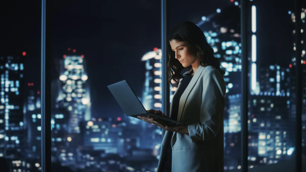 Successful Young Businesswoman Standing and Using Laptop.