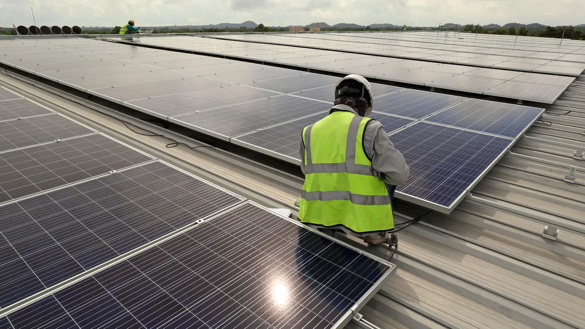 A technician connects cable on a solar rooftop array.