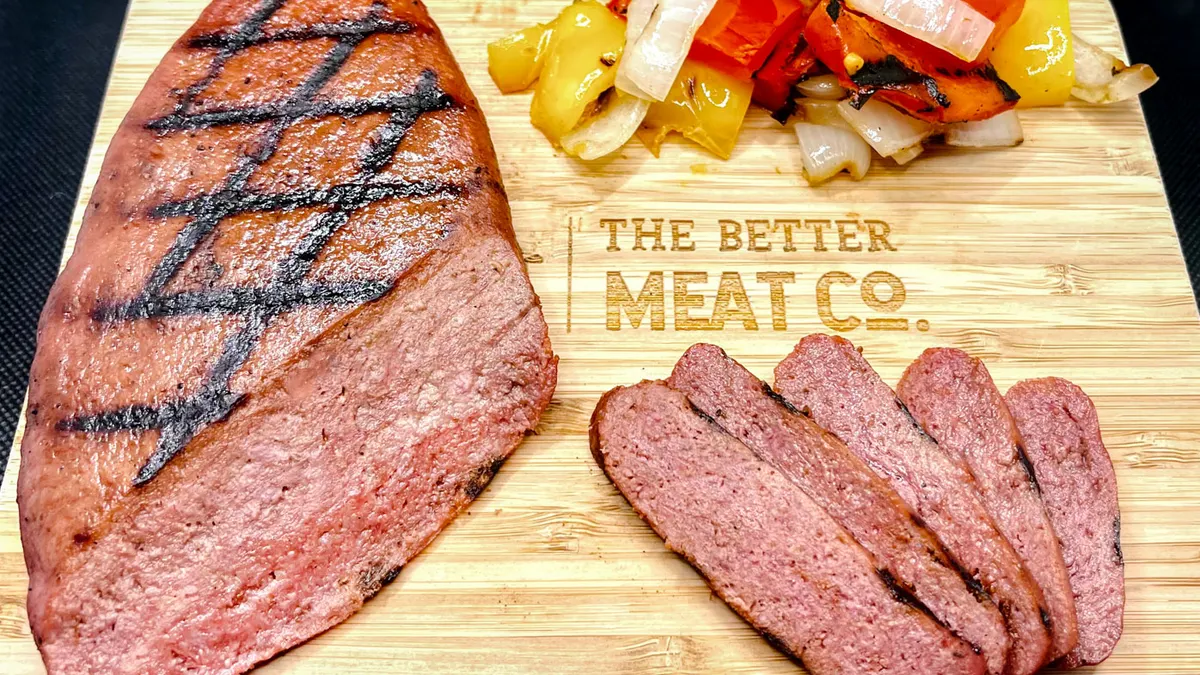 A steak made from Rhiza, Better Meat Co.'s fermented analog, sits on a cutting board with the company's logo.