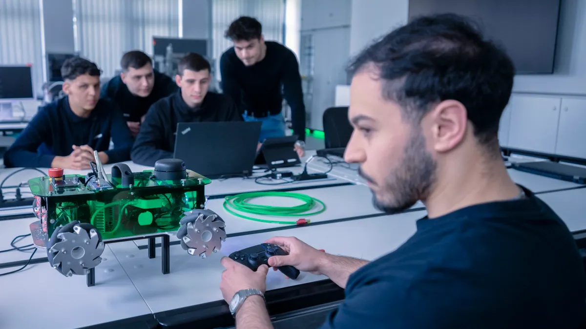 A group of young men work around a laptop and controller rig.