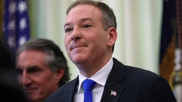 Person wearing blue tie and blue jacket with U.S. flag pin on lapel.