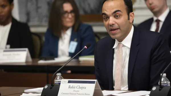 Director of Consumer Financial Protection Bureau Rohit Chopra speaking in front of a desk.