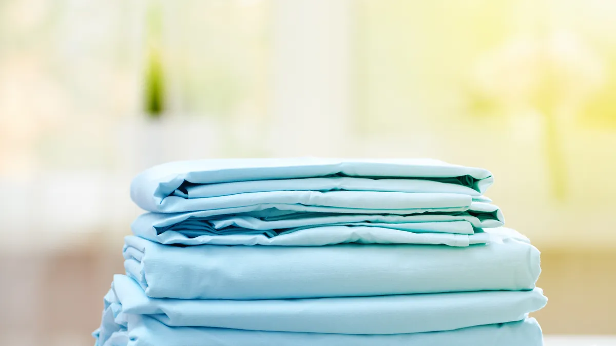 Close-up of a stack of folded blue clean bedding on the table with a blurred background.