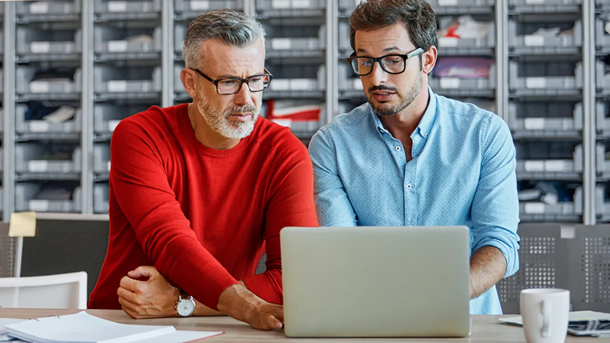 Two colleagues focused on discussion with a laptop