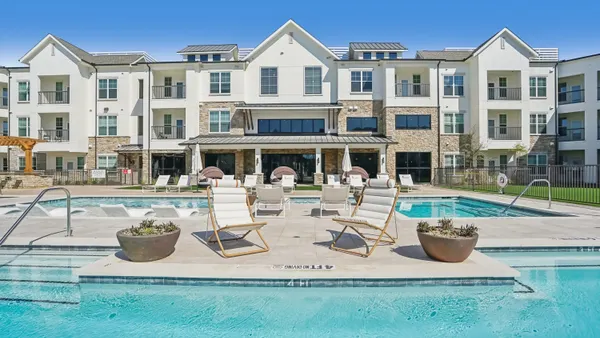 Light-colored apartment property with water in the foreground.