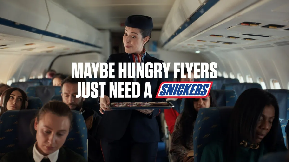 An airline steward passes out Snickers bars on a full flight.