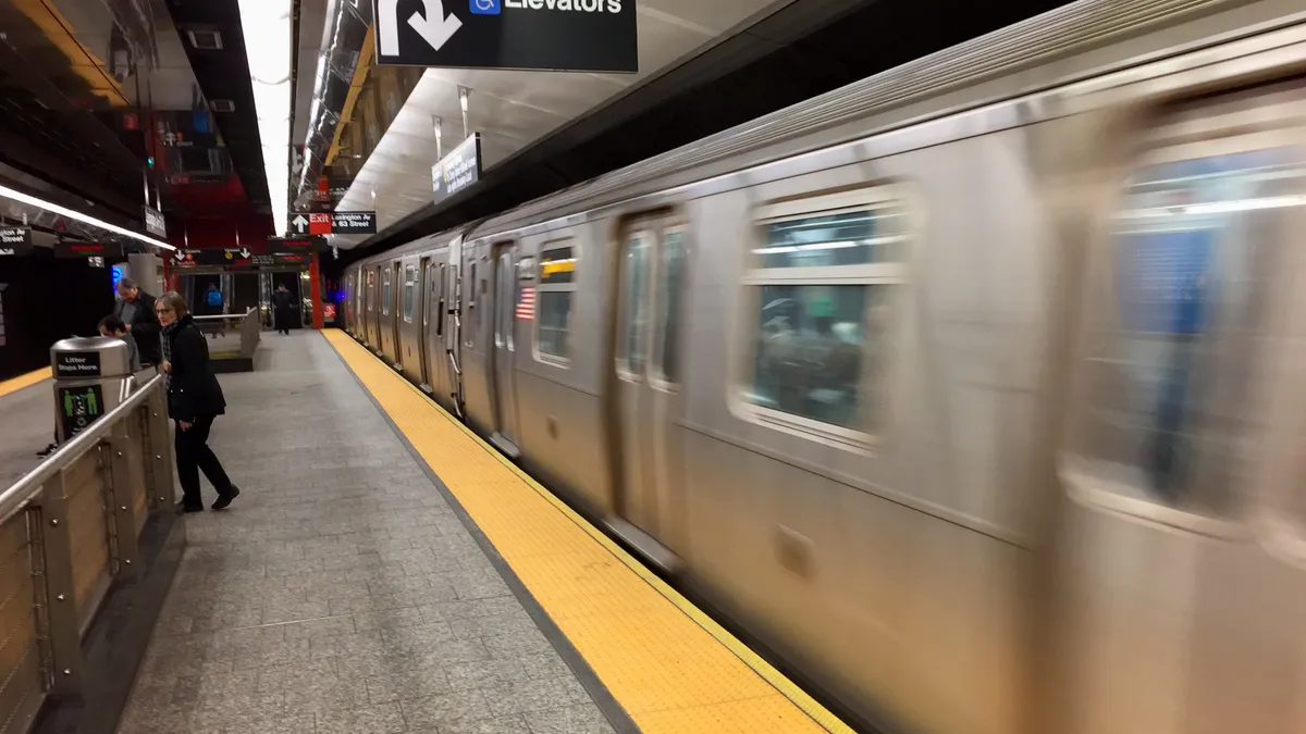 Passengers at a subway station as a train arrives.