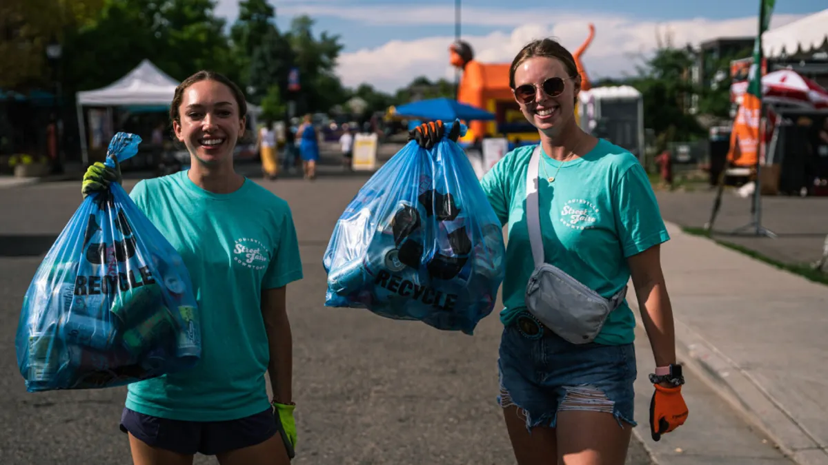 People hold up bags of recycled aluminum cans