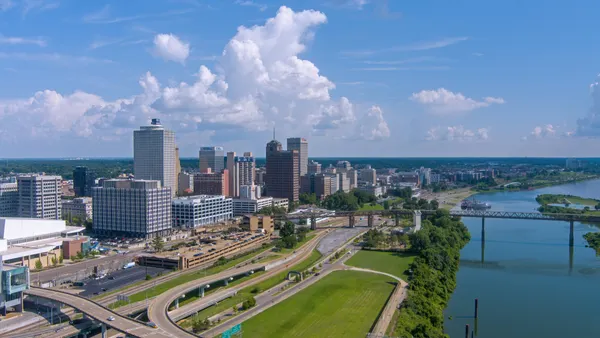 An aerial view of the Memphis, Tennessee downtown is shown, depicting tall buildings alongside a river.