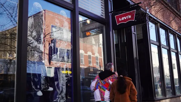 People walk beneath a sign for a Levi's clothing store.
