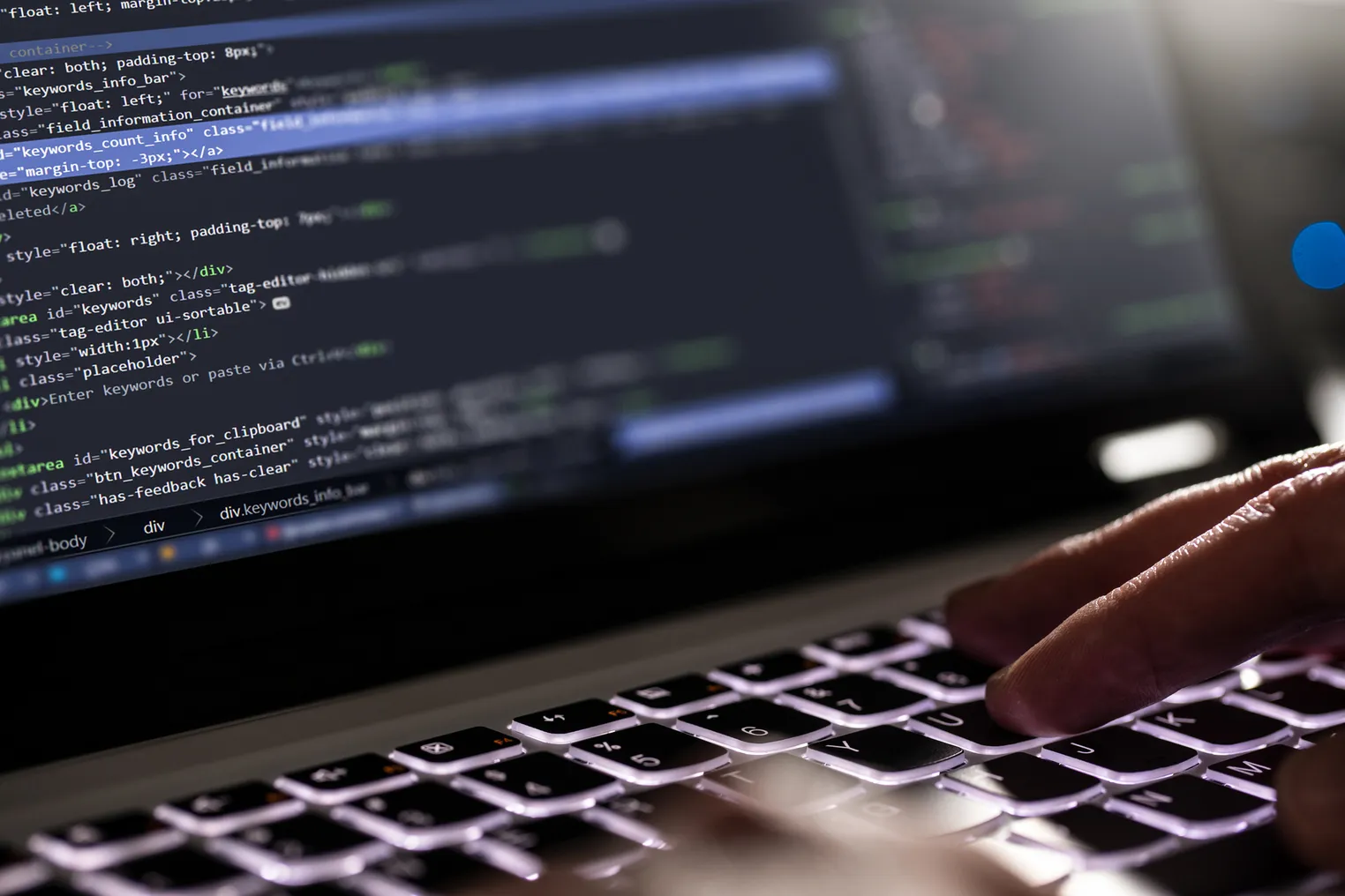 closeup of hands on a keyboard, software code featured in the screen