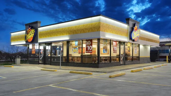 An exterior image of a white restaurant with a yellow decoration and signs that say Church's Chicken