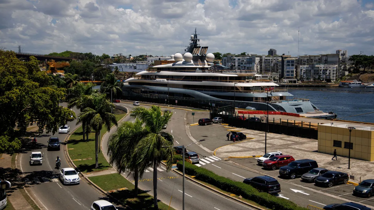 A large yacht sits at a dock in a port.