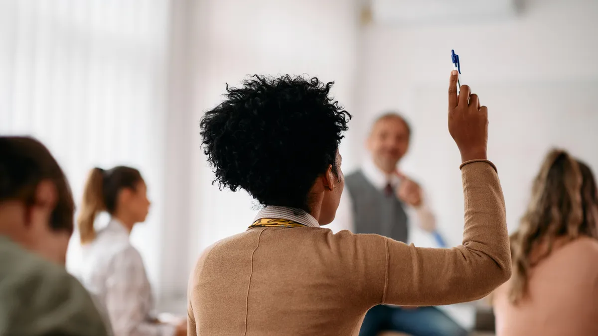 A college student raising their hand in a classroom