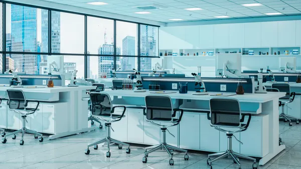 A view of a life sciences lab, with empty chairs and desks in front of a large city-facing window.