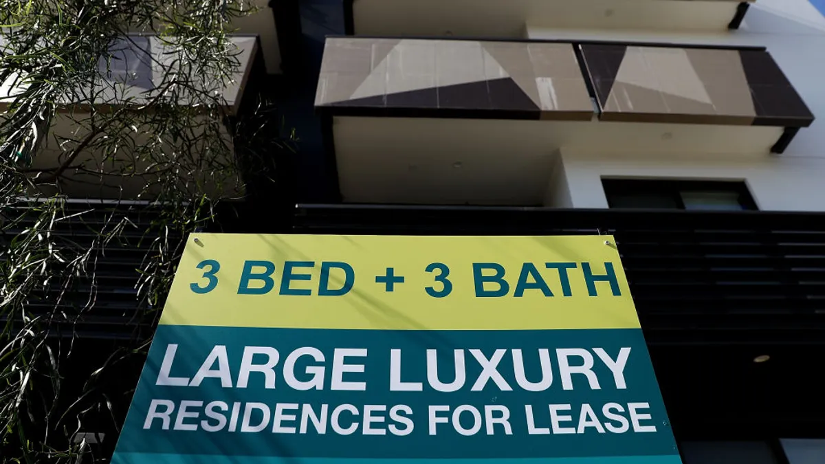 A for lease sign is posted in front of an apartment building.