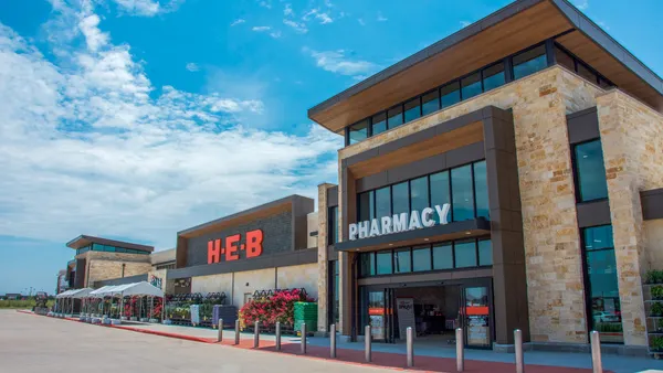 Exterior of supermarket with signs reading "H-E-B" and "pharmacy" on the front.