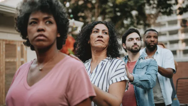 A multi-ethnic group of people stand in an urban area; two women in front, two men in back