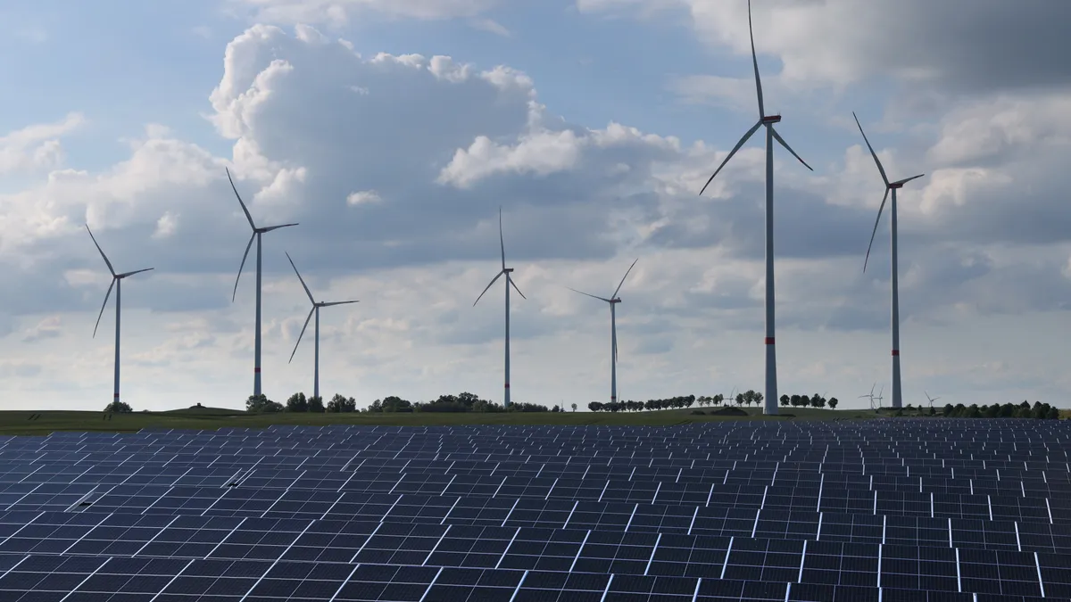 Wind turbines spin behind a solar energy park