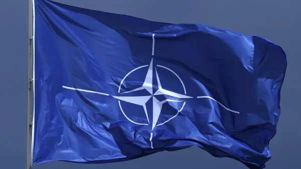 A blue-and-white NATO flag flutters in the breeze
