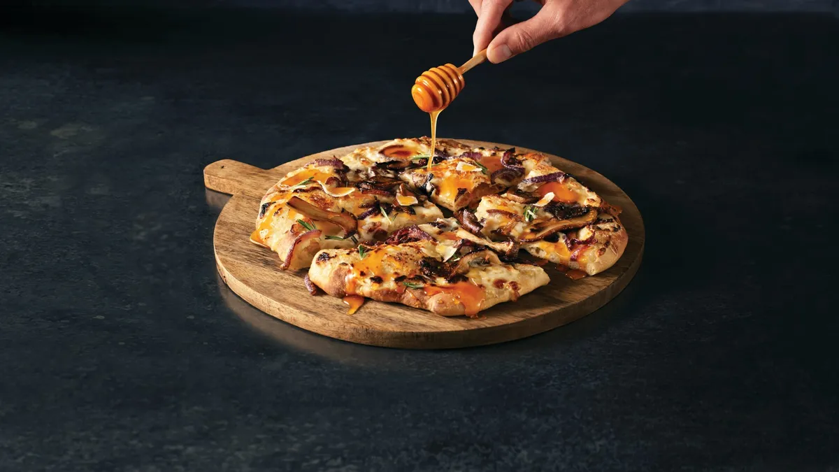 Honey is drizzled over a pizza.