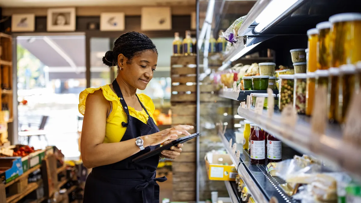 Business owner uses tablet to manage inventory in deli